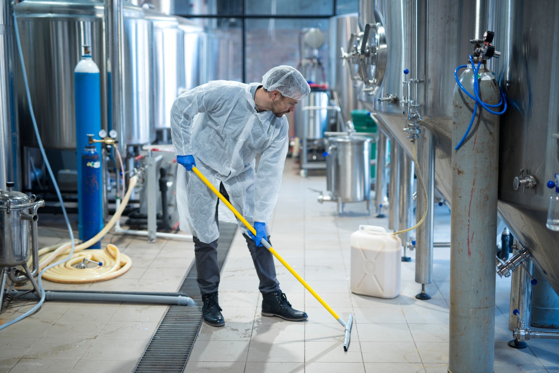 Professional industrial cleaner in protective uniform cleaning floor of food processing plant. Cleaning services. Professional industrial cleaner in protective uniform cleaning floor of food processing plant. Cleaning services.